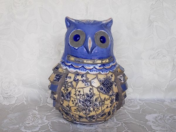 Quite striking this wonderful Ceramic Mosaic Owl Statue with his blue glass eyes surrounded by unglazed gray area. Mosaic pattern made of blue and beige/yellowed white applied broken floral tiles or dishes. The rest glazed with blue, beige and a little white. Unknown manufacturer. Material applied to bottom to help protect furniture. Delight your famiCeramic Mosaic Owl Statue.